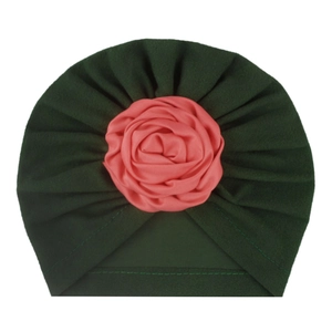 Dettaglio cappello a turbante per neonato in tessuto verde pieghettato e rosa di seta