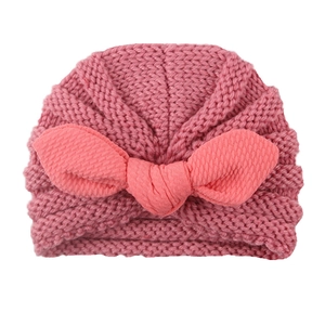 Detail of baby knit hat with large bow and vertical ribbed texture in bright pink color