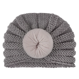 Detailed knit texture and pink donut-shaped knot on a soft grey infant beanie hat
