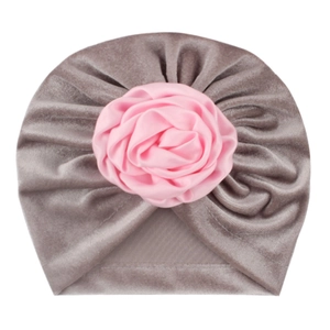 Bonnet turban bébé en velours gris avec une grande fleur rose en satin sur fond blanc