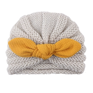 Close-up of baby beige ribbed knit hat with a large ginger yellow fabric bow decoration