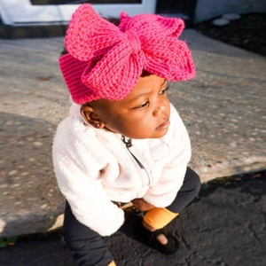 Détail de la texture en tricot d'un bandeau bébé rose rouge avec un grand nœud