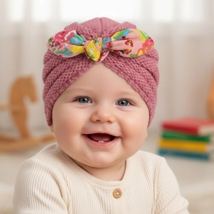 Detail of knit baby turban hat in rose pink featuring a large floral print bow