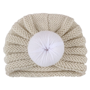Cozy beige knitted baby donut hat with white fabric ruffle ball for winter warmth