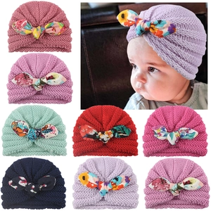 Detail view of baby knitted hats featuring large floral bow designs in various colors
