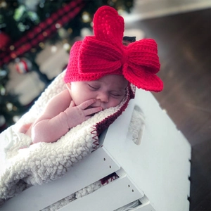 Détail d'un bandeau pour bébé en tricot rouge avec un grand nœud papillon