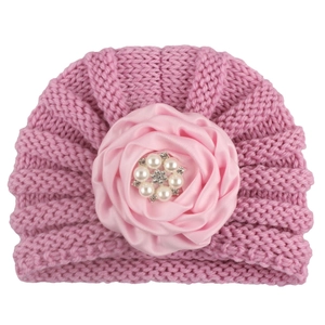 Détail d'un bonnet tricoté rose pour bébé avec rose en satin et perles de strass