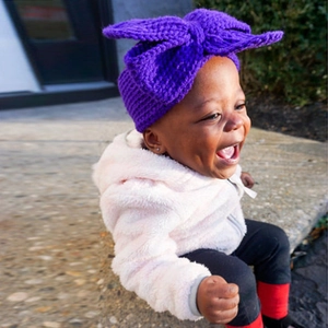 Gros plan d'un bandeau pour bébé en tricot violet avec un grand nœud papillon mignon