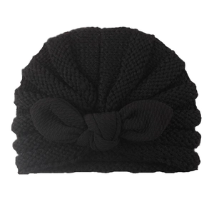 Detailed view of black knitted baby turban hat with decorative bow and textured fabric