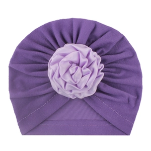 Dettaglio del cappello invernale per neonati con tessuto viola pieghettato e rosa di raso