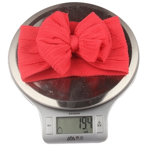 Détail d'un bandeau léger en nylon rouge pour bébé pesant environ 19,4 grammes sur balance