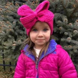 Détail d'un bandeau en tricot magenta pour enfants avec un grand nœud et maille douce