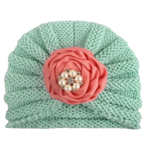 Détail du turban en tricot pour bébé avec fleur en satin et décoration en perles et strass