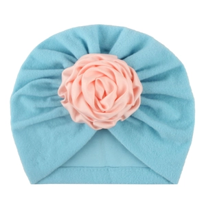 Dettaglio del turbante per neonato azzurro con una decorazione floreale in raso rosa
