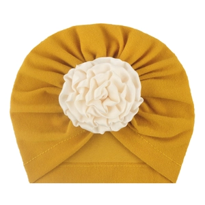 Dettaglio del turbante per neonato giallo brillante con un grande fiore in tessuto crema