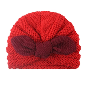 Close-up of baby turban hat featuring a red knitted texture and large bow detail