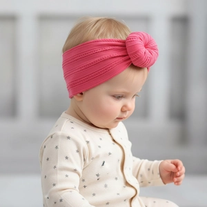 Close-up of baby pink ribbed knit headband featuring a soft 3D donut knot detail