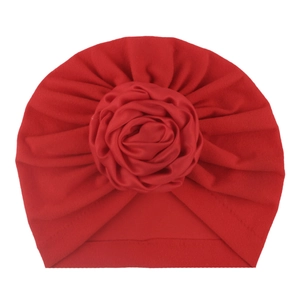 Dettaglio del turbante rosso per neonati con grande rosa in tessuto fatta a mano e pieghe