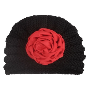 Close-up of black knitted baby headband featuring a large 3D red satin rose flower detail