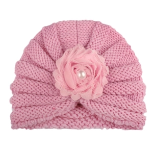 Détail du bonnet en tricot rose pour bébé avec fleur en tissu et perle blanche