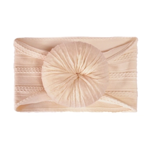 Close-up of cream knit baby headband showing cable patterns and doughnut ball detail