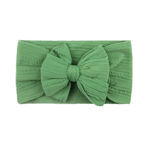 Détail du bandeau bébé vert herbe avec un grand nœud en tricot à texture fine