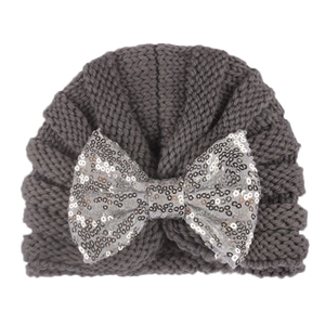 Detail of grey knitted baby hat featuring a large shimmering silver sequin bow