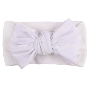 Macro shot of a pure white velvet baby headband with a large decorative bow