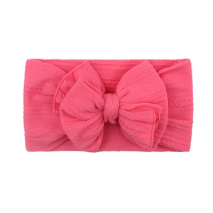 Détail du bandeau tricoté rose vif pour bébé avec motif jacquard et un grand nœud 3D