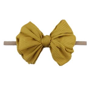 Détail du bandeau pour bébé en tissu côtelé jaune gingembre avec grand nœud élastique