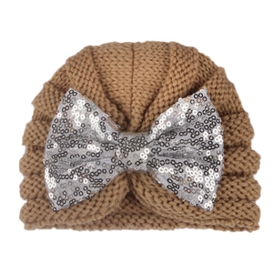 Detailed knit texture of brown baby hat with a shimmering silver sequin bow detail