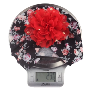 Lightweight baby turban floral hat weighing 23 grams on a digital scale for infants