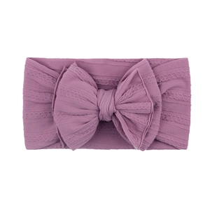 Détail du bandeau bébé en nylon violet avec texture torsadée et grand nœud élégant