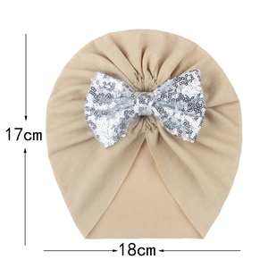 Detailed view of beige baby turban hat with silver sequin bow and 17x18cm dimensions