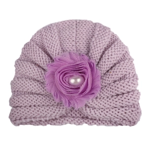 Détail d'un bonnet tricoté lilas pour bébé avec grande fleur en mousseline et perle centrale