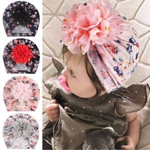 Detail of baby turban hat featuring a large gold-sequined mesh flower and floral patterns