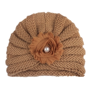 Détail du bonnet tricoté caramel pour bébé avec fleur en mousseline et perle centrale