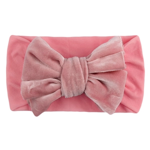 Pink velvet infant headband featuring a large bow on soft elastic wide hair accessory
