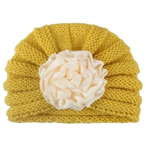 Cute ginger yellow knitted baby hat with a large white satin flower for winter warmth