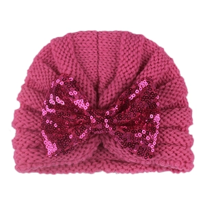 Detailed close-up of rose pink knit baby hat with a sparkling sequined bow decoration
