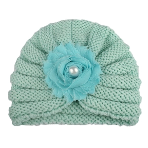 Détail d'un bonnet turban en tricot pour bébé vert menthe avec fleur et perle centrale
