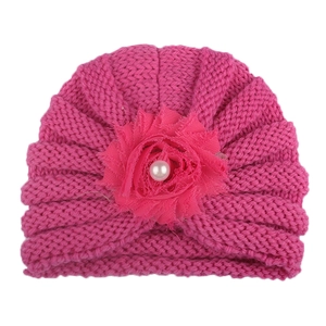 Détail du bonnet tricoté rose pour bébé avec grande fleur en mousseline et perle