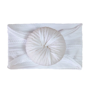 Detailed close-up of white newborn headband featuring a soft knit donut knot design