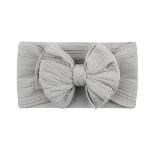 Détail du bandeau bébé en tricot torsadé gris clair avec un grand nœud décoratif