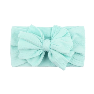Détail de la texture en maille d'un bandeau pour bébé vert menthe avec grand nœud