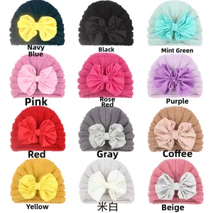 Grid view showing twelve assorted colors of knit baby hats with large fabric bow details