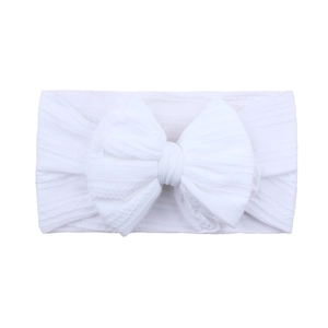 Détail d'un bandeau blanc pour bébé en nylon avec nœud à texture en tricot côtelé doux