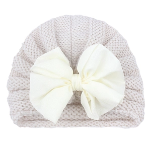 Detail of baby ribbed knit turban hat with large cream satin bow for autumn and winter