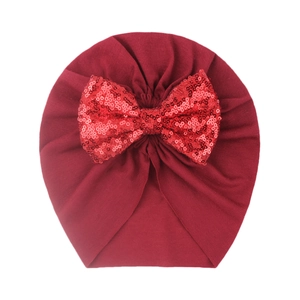 Macro detail of wine red baby turban hat featuring a sparkling red sequined bow accessory