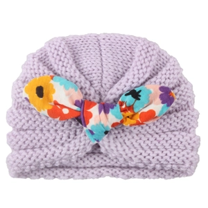Light purple knitted baby hat with a colorful floral fabric bow decoration